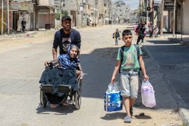 Palestinians carrying their personal belongings flee their homes in the city of Nuseirat in the central Gaza Strip [AFP]