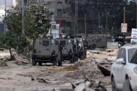 Israeli military vehicles drive along a devastated street in the Nur Shams refugee camp in the occupied West Bank, during a raid on April 19, 2024 [Jaafar Ashtiyeh/AFP]
