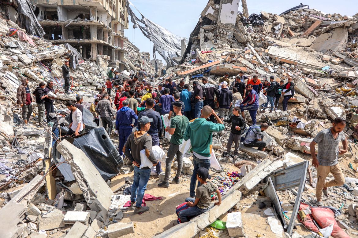 People gather by a destroyed building at the site of a drop of humanitarian aid in the northern Gaza Strip