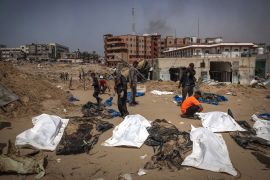 People and health workers unearth bodies found at Nasser Hospital in Khan Yunis in the southern Gaza Strip [AFP]