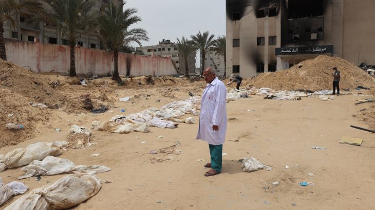 A doctor stands near bodies lined up for identification after they were unearthed from a mass grave found in the Nasser Medical Complex in the southern Gaza Strip on April 25, 2024.edical Complex.
