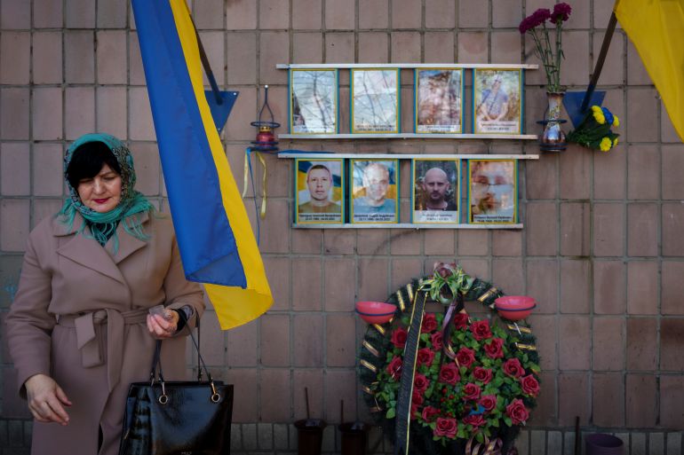 Nataliia Verbova, wife of Andrii Verbovyi, in the top left picture, one of eight men killed by Russian forces near the building on Yablunska street, leaves after lighting a candle at the place where her husband's body was abandoned, in Bucha, Ukraine