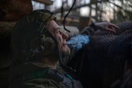 A Ukrainian serviceman from the Azov brigade, known by the call sign Chaos, smokes a cigarette while he waits for a command to fire, in a dugout about 1km (0.6 miles) away from Russian forces on the front line in the Kreminna direction, Donetsk region, Ukraine, Friday, April 12, 2024 [Alex Babenko/AP]