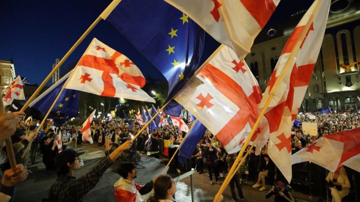 Protesters waving Georgian flags at a protests in Tbilisi. Some are waving EU flags.