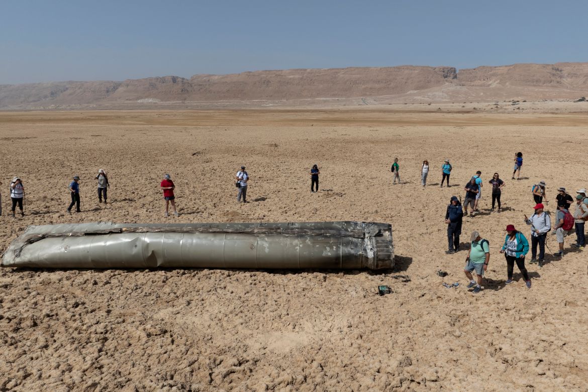 People gather around a component from an intercepted ballistic missile that fell near the Dead Sea in Israel, Saturday, April 20