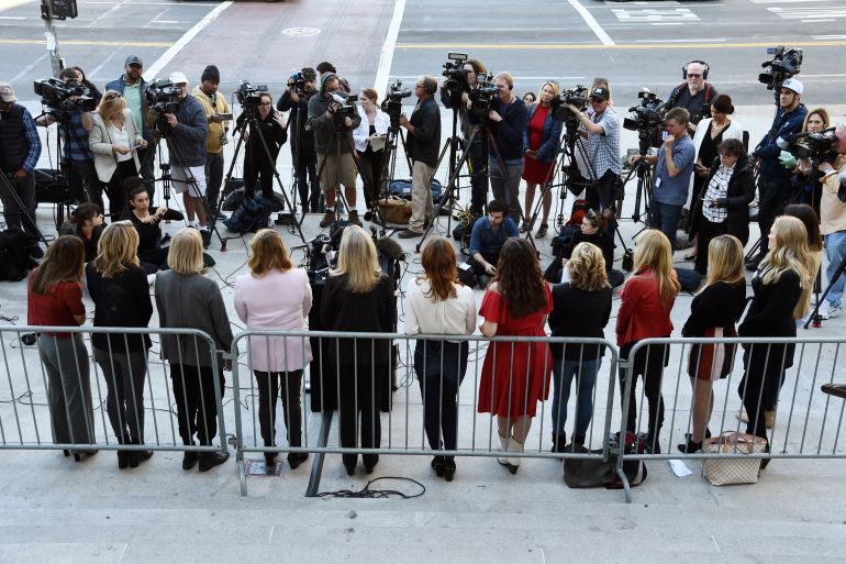 The Silence Breakers, a group of women who spoke out about Harvey Weinstein. They are pictured outside a court in Los Angelese in 2020. They are standing in a line with their backs to the camera, facing a group of journalists.