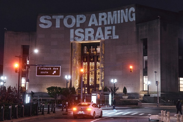 Protesters project a banner reading 'Stop arming Israel'
