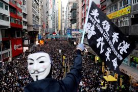 A protester wearing a Guy Fawkes mask waves a flag during a Human Rights Day march, organised by the Civil Human Right Front, in Hong Kong, December 8, 2019 [Danish Siddiqui/Reuters]