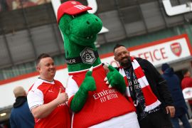 Arsenal fans pose with mascot Gunnersaurus outside the Emirates Stadium [Matthew Childs/Reuters]