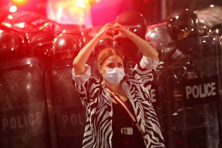 A demonstrator makes a heart-shaped gesture while standing in front of a police cordon during a rally to protest against a bill on "foreign agents" in Tbilisi, Georgia, May 1, 2024. Georgian parliament is set to debate the second reading of the bill described as authoritarian and Russian-inspired by Georgia's opposition and Western countries. REUTERS/Irakli Gedenidze