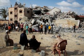 Palestinians look at the site of an Israeli strike on a house, Sunday [Hatem Khaled/Reuters]
