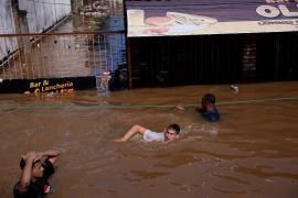 People wade through floodwaters in Canoas, in the Rio Grande do Sul state, Brazil [Amanda Perobelli/Reuters]