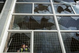 A worker removes shards of glass from a broken window of a school gym damaged by a Russian missile attack in Kharkiv [Sofiia Gatilova/Reuters]