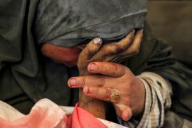 Palestinian woman Buthayna Abu Jazar holds the hand of her son Hazma, who was killed in an Israeli strike in Rafah, in the southern Gaza Strip, on May 9, 2024 [Hatem Khaled/Reuters]
