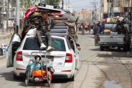 A person sits atop a vehicle loaded with belongings as Palestinians prepare to evacuate after Israeli forces launched a ground and air operation in the eastern part of Rafah [Hatem Khaled/Reuters]