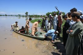 People arrive on a boat across a flooded area after heavy rains in Nowshera district, Khyber Pakhtunkhwa province [File: Abdul Majeed/AFP]