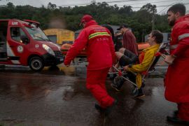 Firefighters evacuate a man from a flooded area in the city centre of Sao Sebastiao do Cai, Rio Grande do Sul State, Brazil, on May 2, 2024 [Carlos Fabal/AFP]