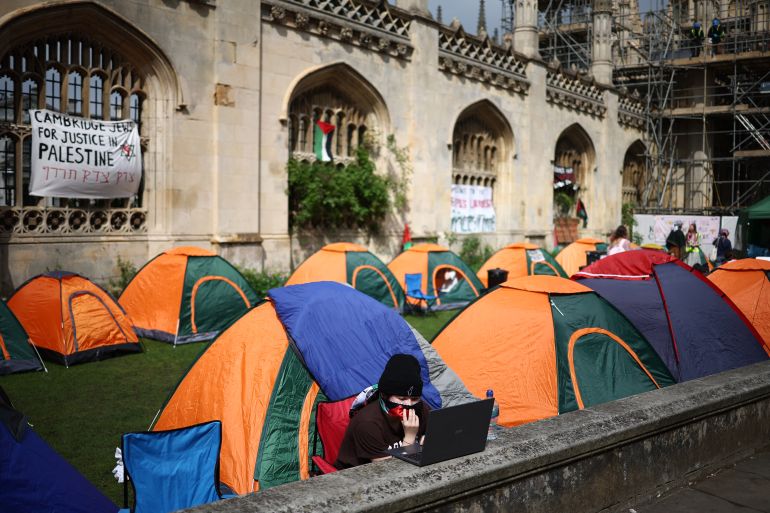 A person works on a laptop computer as they sit by tents during a protest in support of Palestinian people, at Kings College at Cambridge University