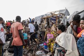 People gather at the site of explosions at a camp for displaced people on the outskirts of Goma in the Democratic Republic of the Congo [Moses Sawasawa/AP]