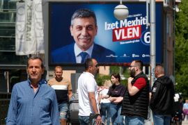 People talk on a street near an electoral poster of Izet Mexhiti from the ethnic Albanian opposition party VLEN, in a street in Skopje, North Macedonia, on May 6, 2024 [Boris Grdanoski/AP Photo]