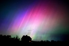 The northern lights flare in the sky over a farmhouse in Brunswick, Maine, United States [Robert F Bukaty/AP Photo]