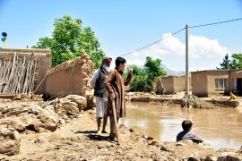 People stand near damaged homes after heavy flooding in Baghlan province in northern Afghanistan. [AP Photo]