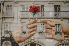 Artwork featuring a red carnation flower is seen on a building in Lisbon, Portugal, on April 23, 2024 [Fredrik Lerneryd/Al Jazeera]