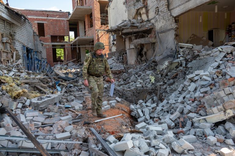 Ukrainian officials inspect the area after the explosion of a Russian guided bomb in the area of apartment buildings in the center of Kharkiv