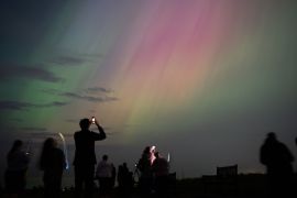 Spectators visit St Mary&#039;s Lighthouse in Whitley Bay in England to see the Aurora Borealis, commonly known as the northern lights [Ian Forsyth/Getty Images]